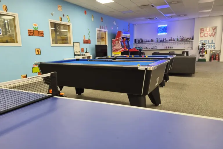 Pool tables in the middle of a large space, walls with Super mario bros layout